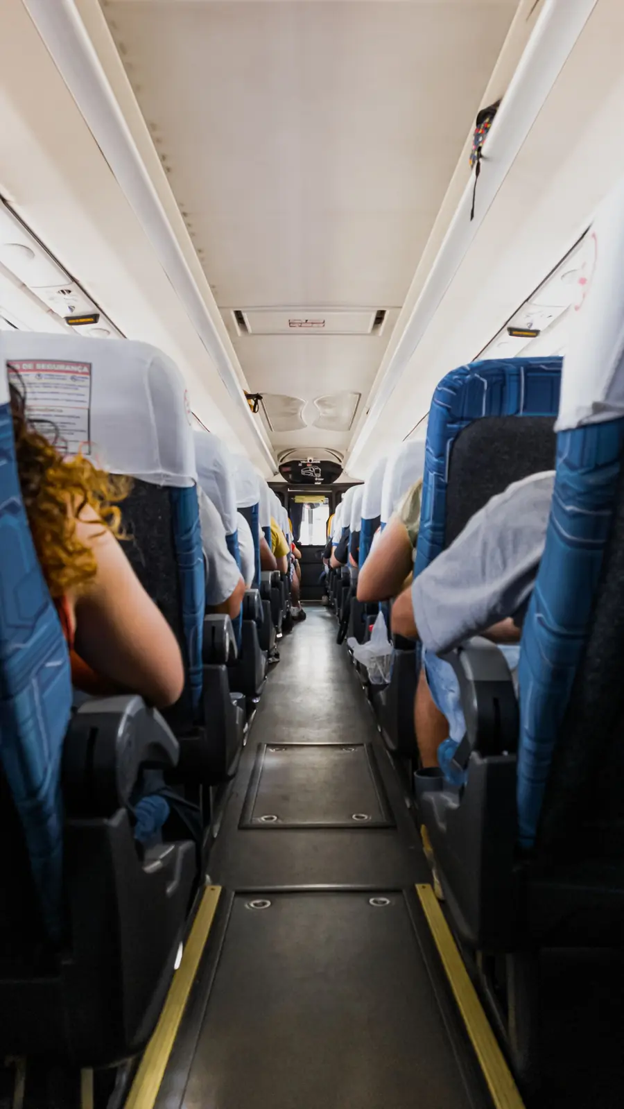 Pasillo interior de un bus con pasajeros sentados